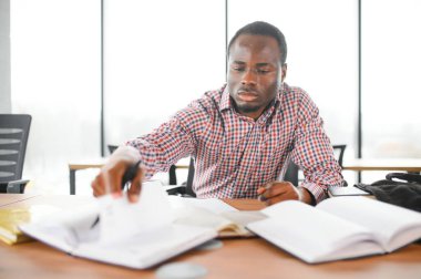 Üniversite sınıfında oturan erkek öğrenci başka tarafa bakıyor ve gülümsüyor. Lisedeki derste oturan adam..