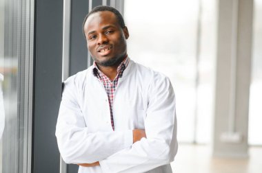 Koridorda Afrikalı bir doktor var. Klinikte fotokopi alanı olan tablet bilgisayar kullanan kendinden emin erkek doktorun portresi.