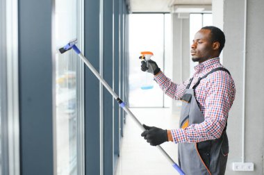 Mutlu erkek işçi cam sileceği ve püskürtülen ilaç şişe ile Temizleme.