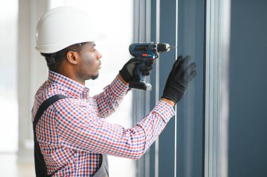 İnşaat işçisi plastik pencereyi tornavidayla tamir ediyor. Pankart tasarımı