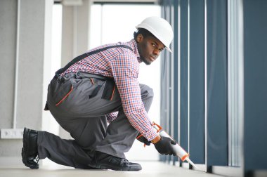 Evdeki oturma odasına plastik pencereler monte eden ya da ayarlayan işçi