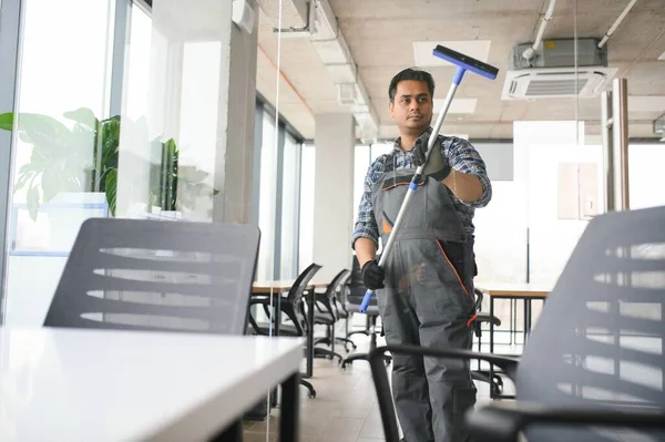 Male professional cleaning service worker cleans the windows and shop windows of a store with special equipment.