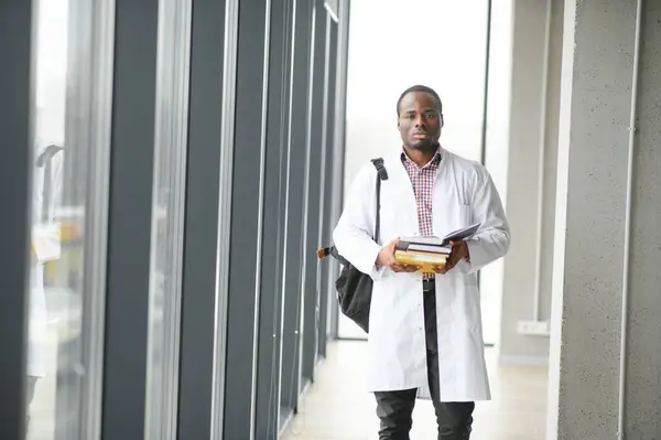 Black male doctor student wearing a lab coat with book.