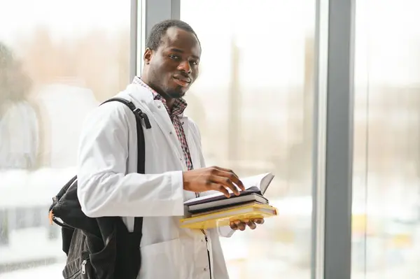 Portrait of medical student. Young African American doctor read book, and documents preparing for exams.