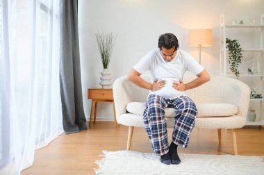 Hint ve Arap kökenli üzgün bir adam, ellerini karnının üstünde tutuyor, midesinde acı çekiyor, zehirlenme, spazm, mide sorunları yaşıyor..