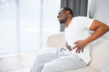 Siyahi Adam 'ın karın ağrısı var. Karın spazmı yüzünden acı çekiyor. Karnına dokunuyor. Karın ağrısı, mide iltihabı ve apandisit konsepti.