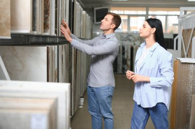 Güzel genç bir çift, evlerinin tamiri için seramik fayansları seçiyor..