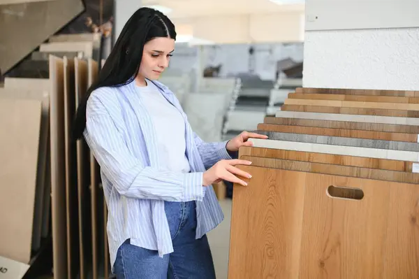 Young woman choosing laminate floor for home renovation.