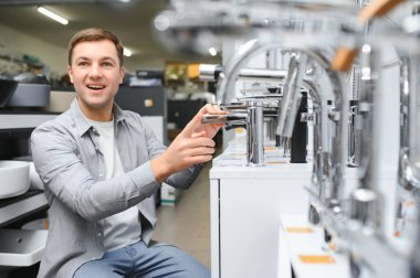 Adam inşaat süpermarketinde banyo musluğu seçiyor, evdeki su tesisatını tamir ediyor..