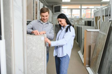 Yeni ev zeminleri için seramik ve fayanslı bir çift. Mobilya dükkanında seçiyorlar..