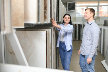 Güzel genç bir çift, evlerinin tamiri için seramik fayansları seçiyor..