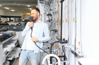 Tesisat bölümündeki nalbur dükkanındaki bir müşteri mutfak için musluk seçiyor..