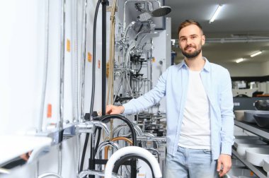 Tesisat bölümündeki nalbur dükkanındaki bir müşteri mutfak için musluk seçiyor..