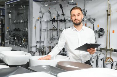 Tesisatçı dükkanında kağıt tabletli mutlu bir satıcı..