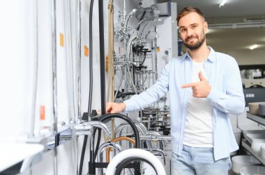 Tesisat bölümündeki nalbur dükkanındaki bir müşteri mutfak için musluk seçiyor..