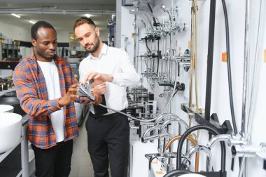 Muslukları seçen Afrikalı genç bir adam su tesisatı dükkanının yanında satıcıyla duruyor..