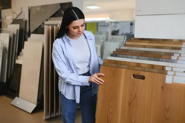 woman choosing laminate floor design from samples in flooring store.