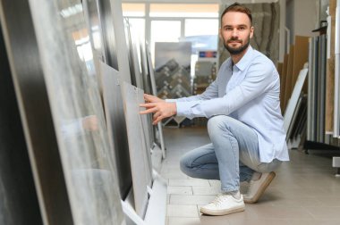 Markette fayans seçen genç bir adam.