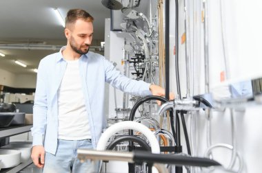 Büyük bir çeşme çeşmesi seçimi. Adam hijyenik eşya dükkanından ürün seçiyor..