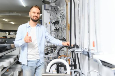 Büyük bir çeşme çeşmesi seçimi. Adam hijyenik eşya dükkanından ürün seçiyor..