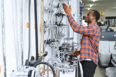 Büyük bir çeşme çeşmesi seçimi. Afrikalı Amerikalı bir adam hijyenik eşya dükkanından bir ürün seçiyor..