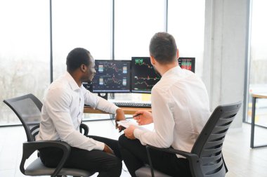 İki güler yüzlü iş adamı, finans analisti veya yatırım danışmanı ellerinde laptop ve belgelerle ofiste oturuyorlar, iş analizi, danışmanlık hizmetleri, takım portresi