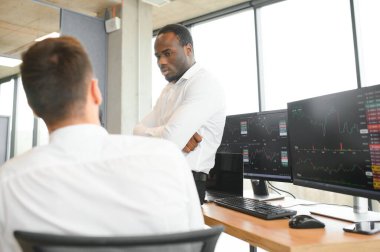 Ofiste oturan iki başarılı tüccar, finans piyasası grafiğindeki kripto para biriminin verilerini kontrol ediyor, monitöre işaret ediyor..