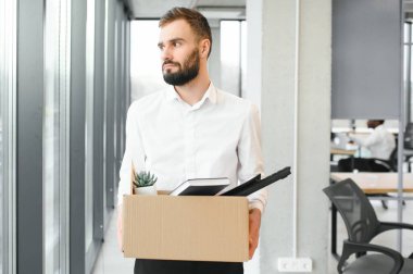 Genç yakışıklı işadamı karton kutu ışık modern ofiste. Son günün. Üzgün ofis çalışanı işten.