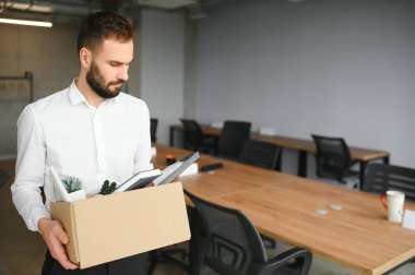 Sad Fired. Let Go Office Worker Packs His Belongings into Cardboard Box and Leaves Office. Workforce Reduction, Downsizing, Reorganization, Restructuring, Outsourcing. Mass Unemployment Market Crisis.