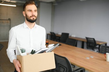 Genç yakışıklı işadamı karton kutu ışık modern ofiste. Son günün. Üzgün ofis çalışanı işten.