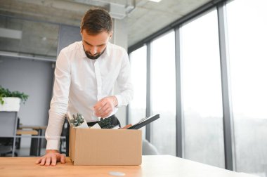 Sad Fired. Let Go Office Worker Packs His Belongings into Cardboard Box and Leaves Office. Workforce Reduction, Downsizing, Reorganization, Restructuring, Outsourcing. Mass Unemployment Market Crisis.