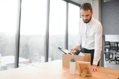 Man by dismissal. Guy lost job. Fired manager in company. Dismissal box in hands of employee. Man office worker disappointed by dismissal. Fired male in blurred office. Discharge company employees