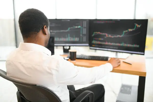 Stock Market Day Trader Working on Computer with Multi-Monitor Workstation with Real-Time Investmentment Charts.