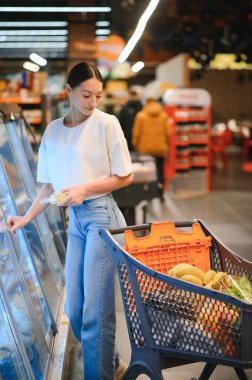 Markette ürünlere bakan mutlu genç bir kadın. Gülümseyen kadın süpermarkette alışveriş yapıyor.