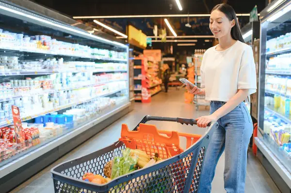 Groceries Shopping. Portrait Of Smiling Happy Woman Leaning On Trolley Cart In Supermarket.