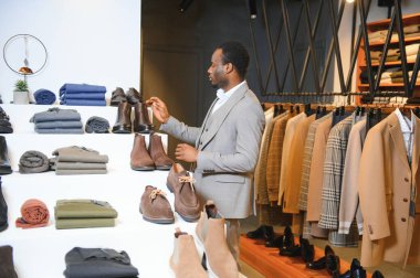 Genç yakışıklı bir adam dükkanda ayakkabı seçiyor..