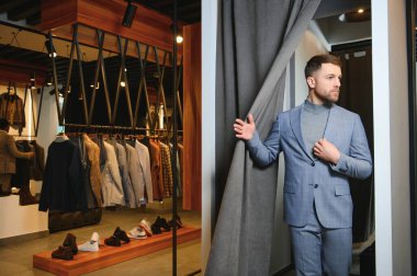 Gülümseyen, seyir ve klasik seçme Modern genç yakışıklı işadamı uygun takım elbise dükkanı.