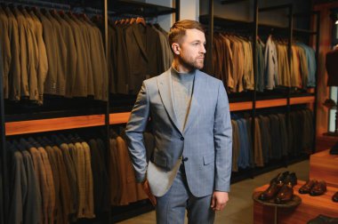 Gülümseyen, seyir ve klasik seçme Modern genç yakışıklı işadamı uygun takım elbise dükkanı.