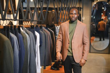 Premium erkek giyim mağazasında şık takım elbiseli Afrikalı bir işadamı.