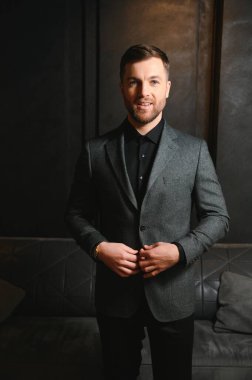 Arkaplanda zarif bir takım elbise içindeki yakışıklı bir adamın portresi..