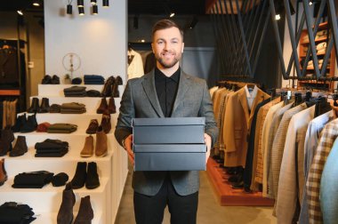 Giysi mağazasında içinde yeni kıyafetler ya da ayakkabılar olan kutular tutan mutlu müşteriler..