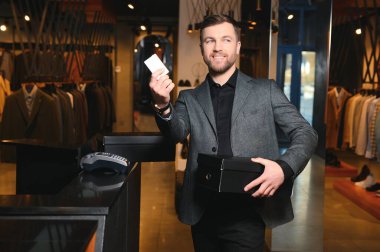 Kutular dolusu yeni kıyafet ve ayakkabı taşıyan ve kredi kartıyla ödeme yapan mutlu müşteriler..