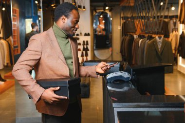 Kutu kutu yeni kıyafet ya da ayakkabı taşıyan ve kredi kartıyla ödeme yapan mutlu müşteriler..