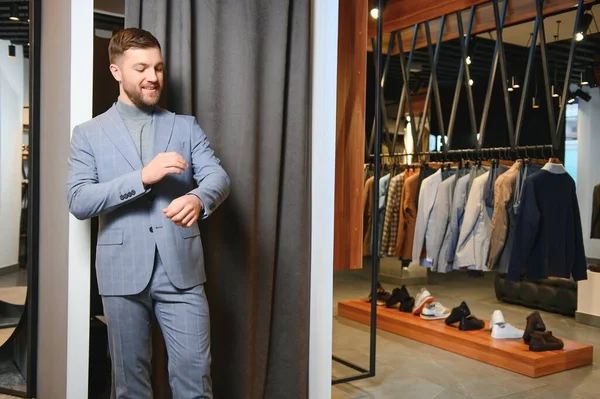 Gülümseyen, seyir ve klasik seçme Modern genç yakışıklı işadamı uygun takım elbise dükkanı.