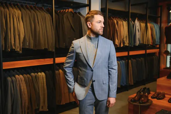 Gülümseyen, seyir ve klasik seçme Modern genç yakışıklı işadamı uygun takım elbise dükkanı.