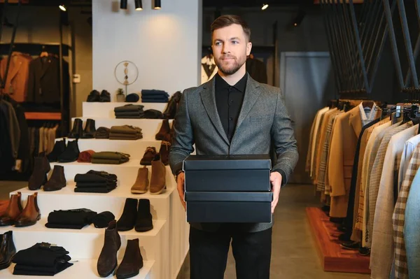 Afro-Amerikalı neşeli bir adam giyim mağazasında alışveriş torbaları taşıyor. Moda butiği..