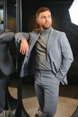 Erkek giyim mağazasında aynada takım elbise deneyen adam..