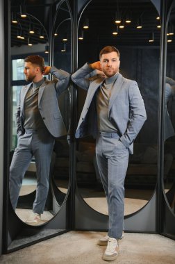 Erkek giyim mağazasında aynada takım elbise deneyen adam..