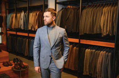 Gülümseyen, seyir ve klasik seçme Modern genç yakışıklı işadamı uygun takım elbise dükkanı.