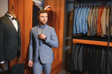 Gülümseyen, seyir ve klasik seçme Modern genç yakışıklı işadamı uygun takım elbise dükkanı.